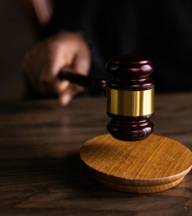 A gavel striking a sound block, symbolizing justice and legal authority in a courtroom setting.